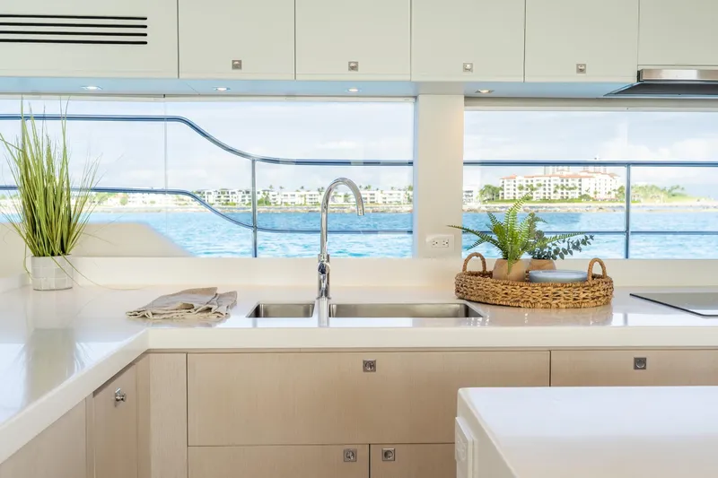  Yacht Photos Pics Modern yacht kitchen interior with ocean view, featuring sleek countertops and decorative plants.