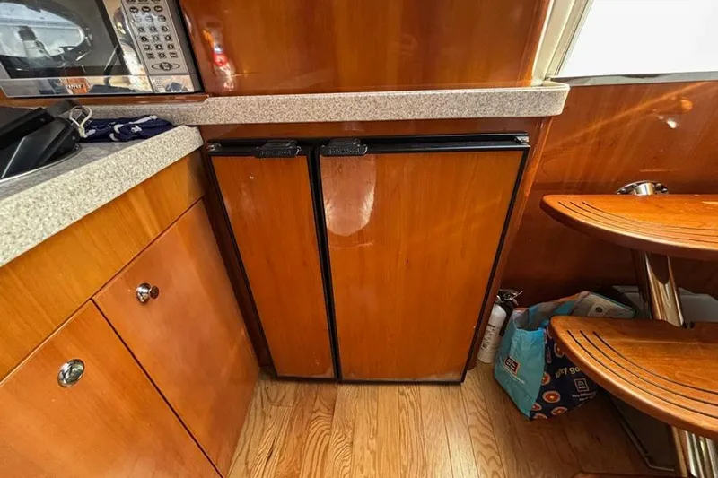  Yacht Photos Pics 2005 Regal Commodore 4260 yacht interior with wooden cabinetry and compact kitchen appliances.