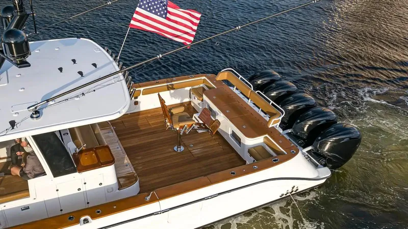 Next To Sell Yacht Photos Pics 2020 HCB Estrella boat with American flag, wooden deck, and multiple outboard engines.