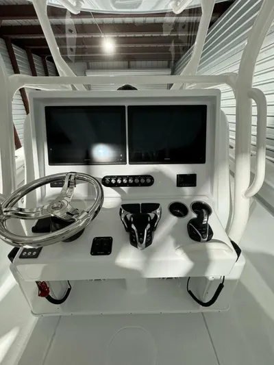 36 Yellowfin Yacht Photos Pics 2024 Yellowfin 36 boat console with dual screens and steering wheel in a storage facility.