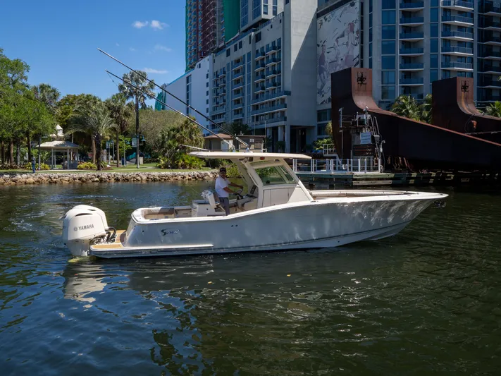  Yacht Photos Pics 2015 Scout 320 LFX boat cruising near urban waterfront with modern buildings.