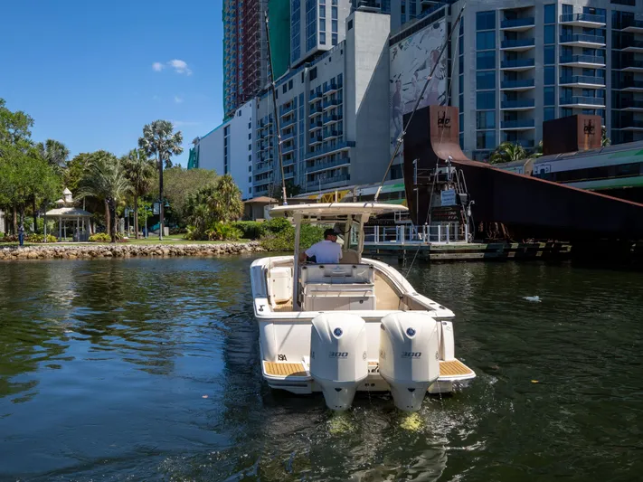  Yacht Photos Pics 2015 Scout 320 LFX boat cruising near urban waterfront buildings.