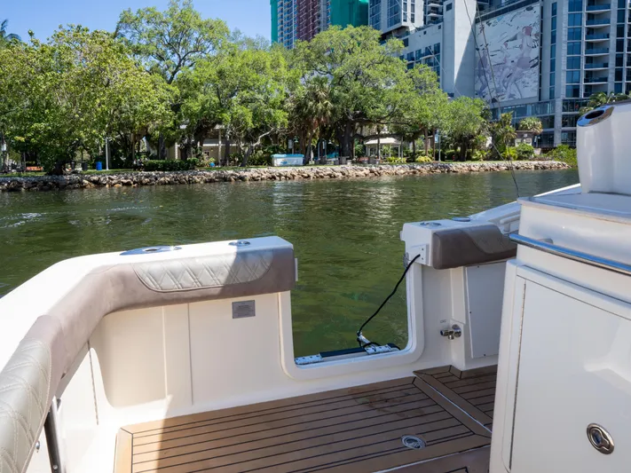  Yacht Photos Pics 2015 Scout 320 LFX boat docked by a scenic waterfront with trees and buildings.