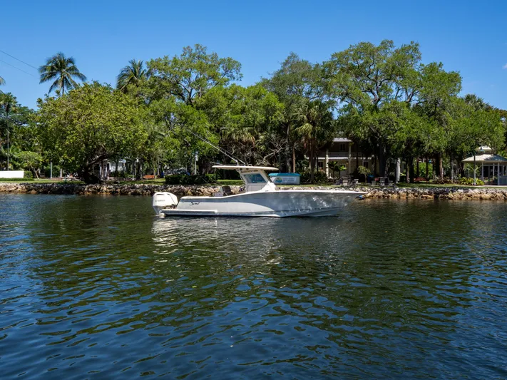  Yacht Photos Pics 2015 Scout 320 LFX boat on a serene lake with lush green trees.