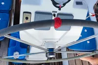 Steering wheel of a 2019 Custom Patago 40 yacht with blue seating and wooden deck.