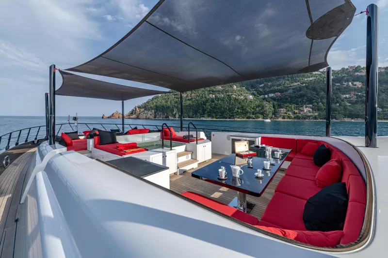 Black Legend Yacht Photos Pics Luxurious 2017 Mangusta 165E yacht deck with red seating, ocean view, and shaded canopy.