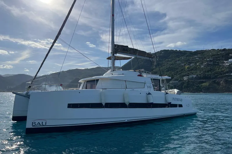  Yacht Photos Pics 2020 Bali 4.3 catamaran sailing on clear blue waters near a scenic coastline.