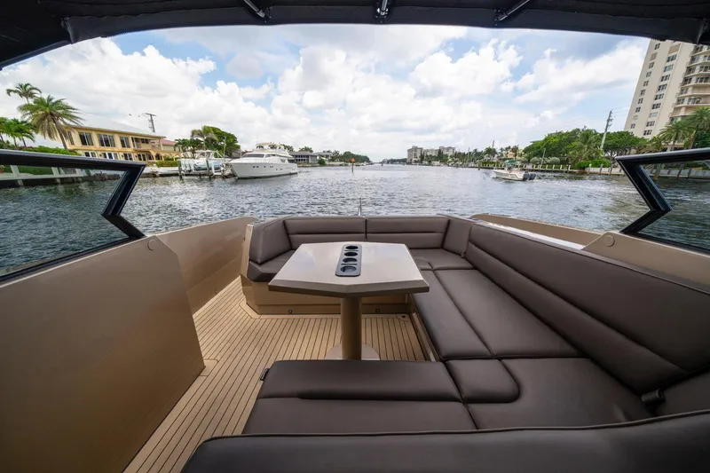 Cobra Yacht Photos Pics Luxurious 2022 Vanquish Yachts VQ45 interior with waterfront view, featuring sleek seating and table.