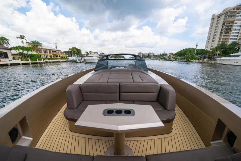 Cobra Yacht Photos Pics 2022 Vanquish Yachts VQ45 luxury yacht interior with seating and table on a scenic waterway.
