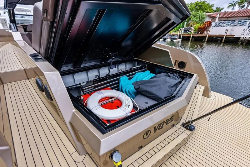 Cobra Yacht Photos Pics 2022 Vanquish Yachts VQ45 storage compartment with life preserver and gear, docked by waterfront homes.