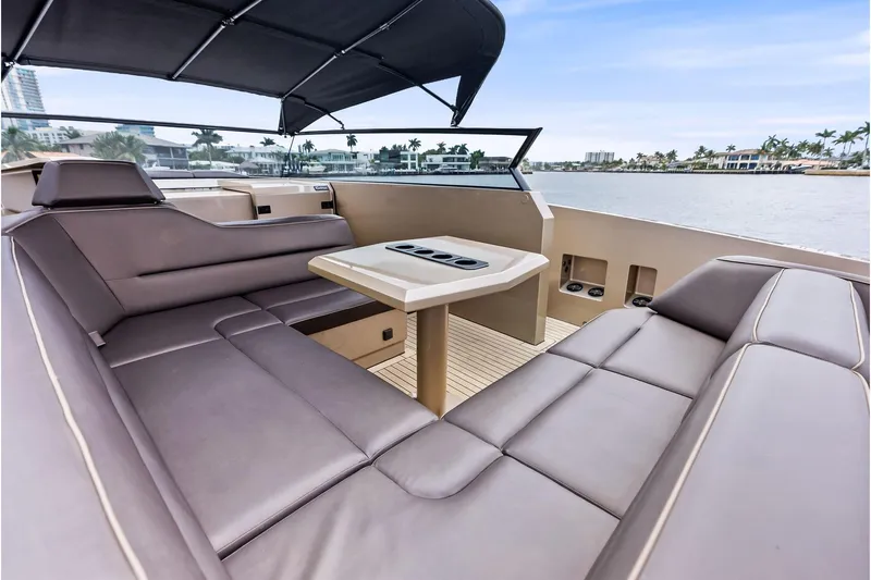 Cobra Yacht Photos Pics Luxurious 2022 Vanquish Yachts VQ45 interior with plush seating and table, overlooking serene waterfront.