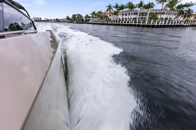 Cobra Yacht Photos Pics Vanquish Yachts VQ45 cruising on water near luxury waterfront homes, 2022 model.