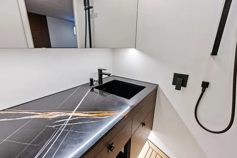 Cobra Yacht Photos Pics Luxurious 2022 Vanquish Yachts VQ45 bathroom with sleek black marble countertop.