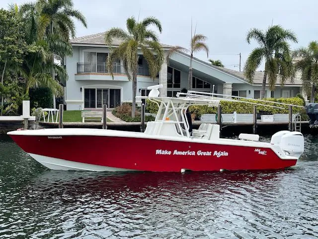  Yacht Photos Pics 2016 SeaVee 340Z boat with red hull, docked near waterfront home, palm trees in background.
