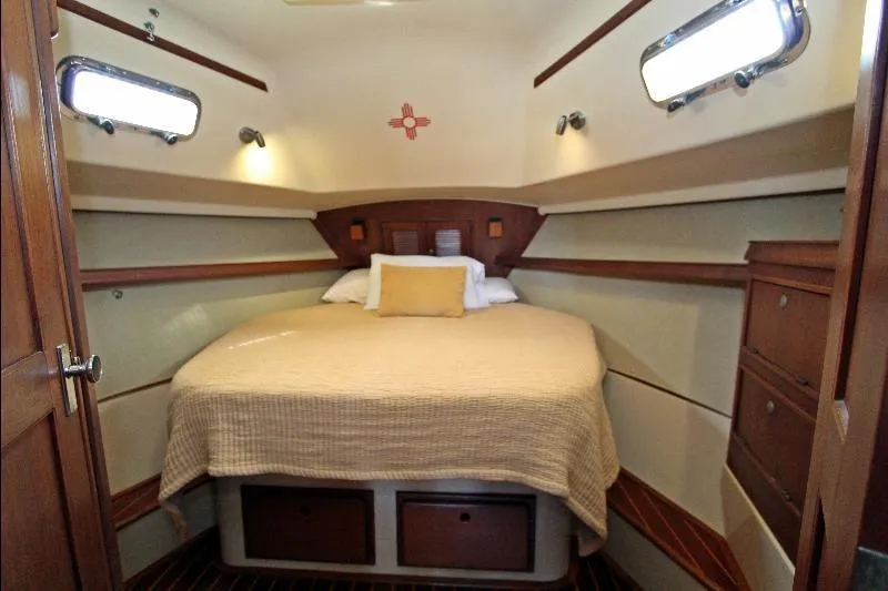  Yacht Photos Pics Cozy cabin interior of 1999 Island Packet 380 sailboat with bed and wooden storage.