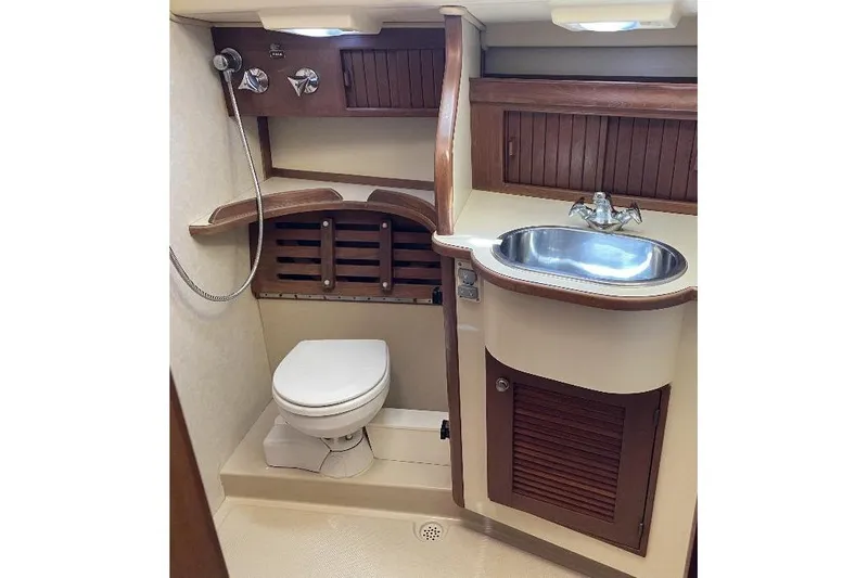  Yacht Photos Pics 1999 Island Packet 380 yacht bathroom with toilet, sink, and wooden cabinetry.
