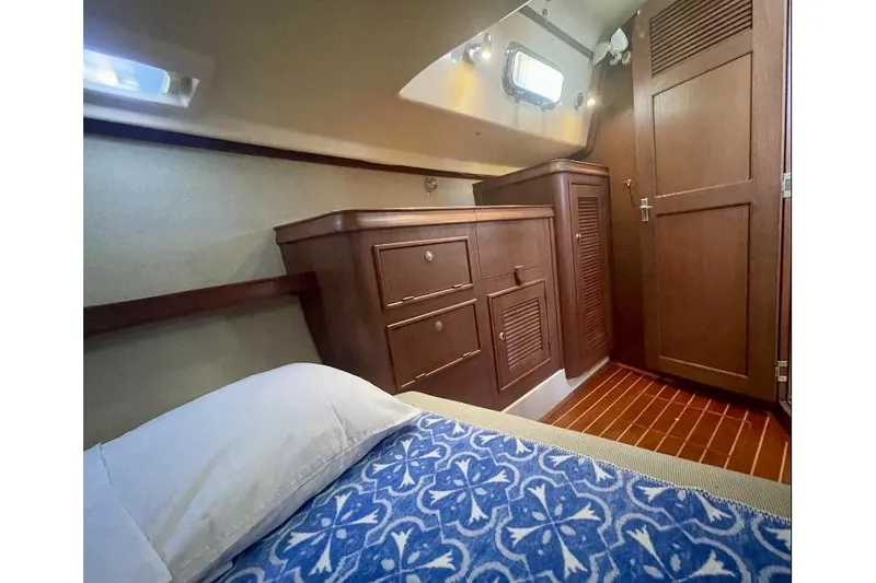  Yacht Photos Pics Cozy cabin interior of 1999 Island Packet 380 sailboat with wooden cabinetry and patterned bedding.