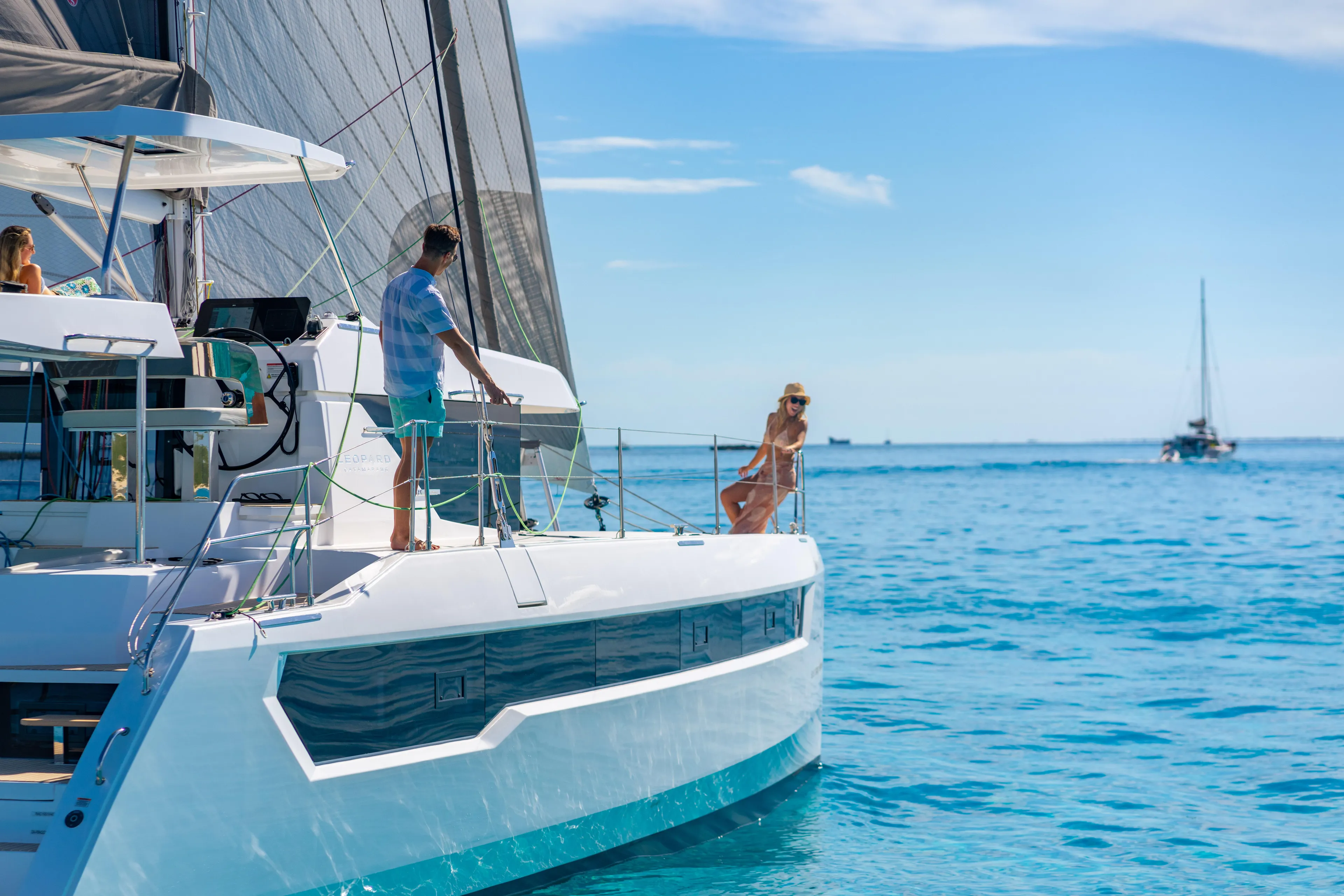 C1019 Yacht Photos Pics 2025 Leopard 46 yacht sailing on clear blue ocean with people relaxing on deck.