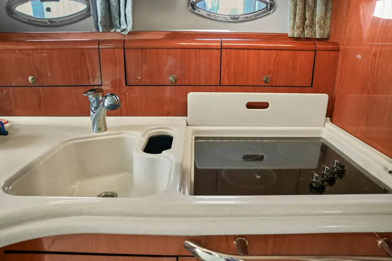  Yacht Photos Pics 2001 Sea Ray 510 Sundancer kitchen with sink and stovetop, wooden cabinetry.