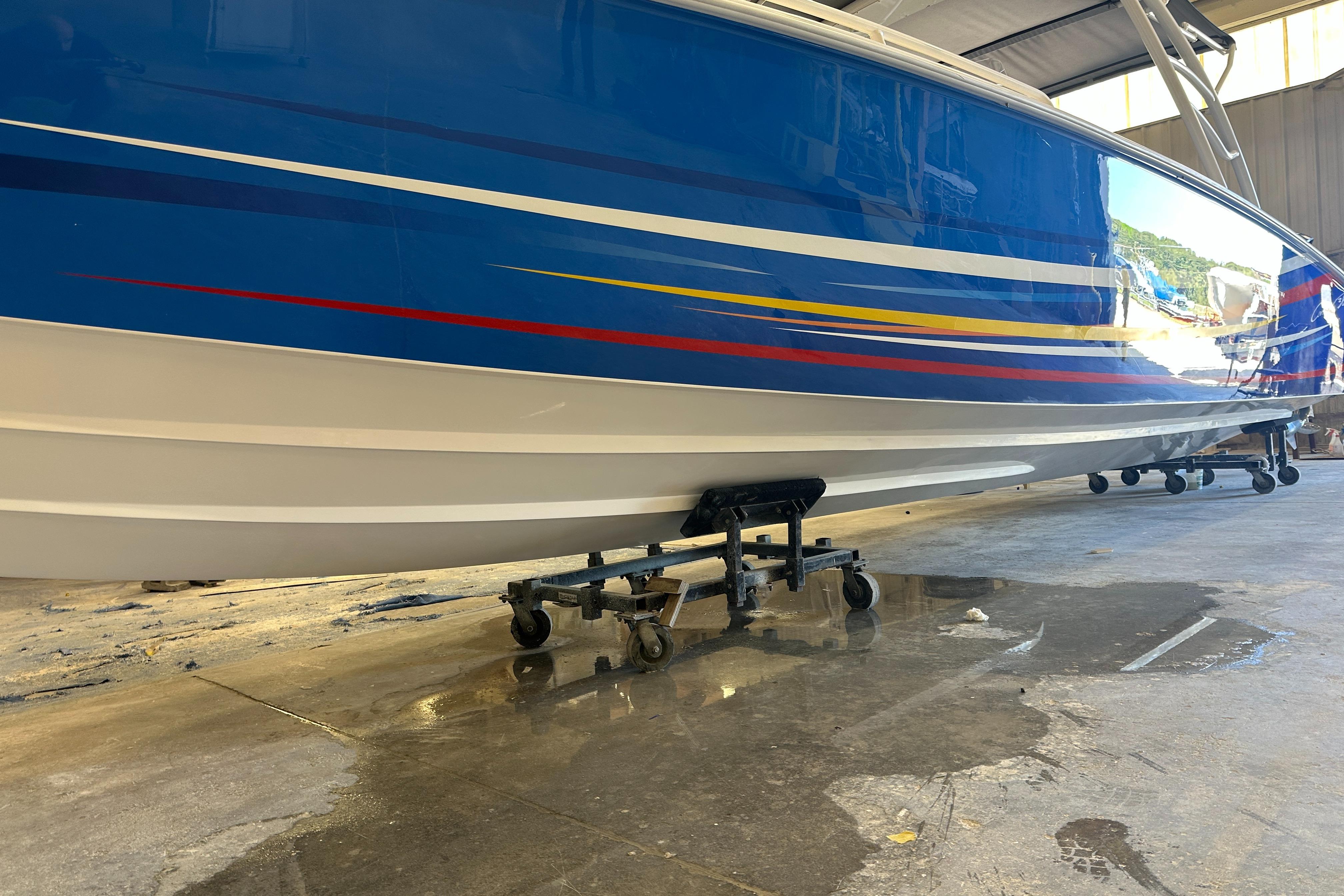 Blue and white Concept 36 boat from 2014 on a wheeled stand in a garage.