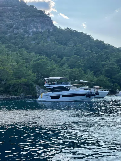  Yacht Photos Pics 2023 Azimut Fly 53 yacht on serene water, surrounded by lush greenery.