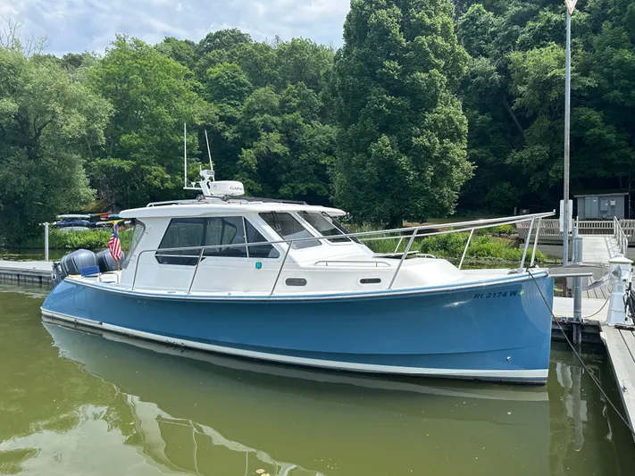 Yacht Photos Pics 2018 True North 34OE boat docked, surrounded by lush green trees.