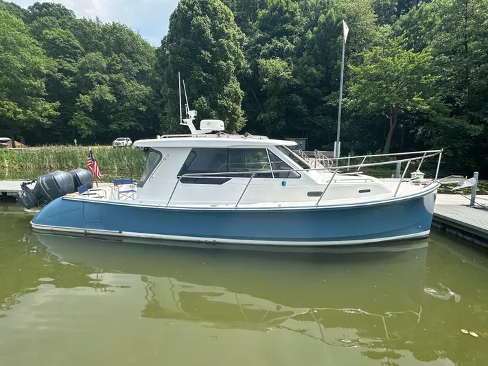  Yacht Photos Pics 2018 True North 34OE boat docked on calm water, surrounded by lush greenery.