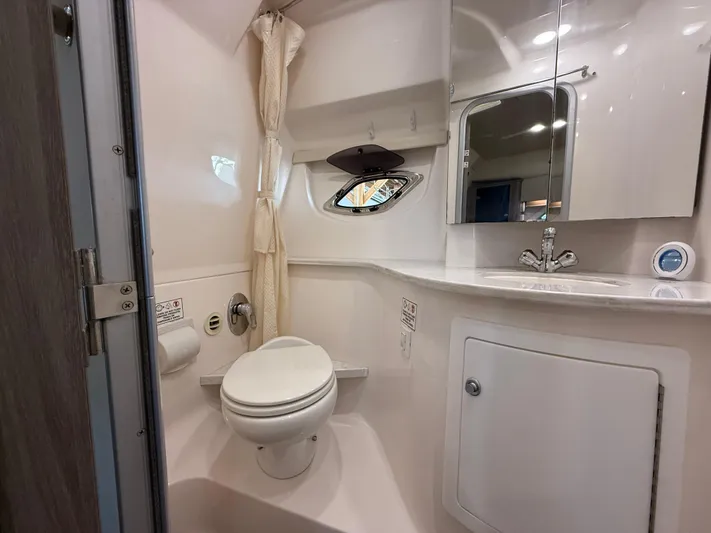 Social Distance Yacht Photos Pics 2019 Regal 35 Sport Coupe bathroom with toilet, sink, mirror, and porthole window.