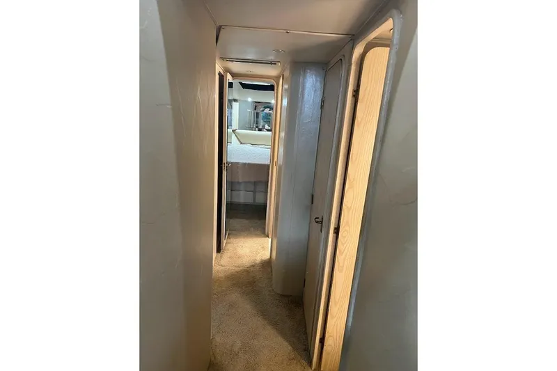 Our Trade II Yacht Photos Pics Narrow hallway inside 1996 Ocean Yachts 48 Super Sport, featuring carpeted flooring and wooden doors.
