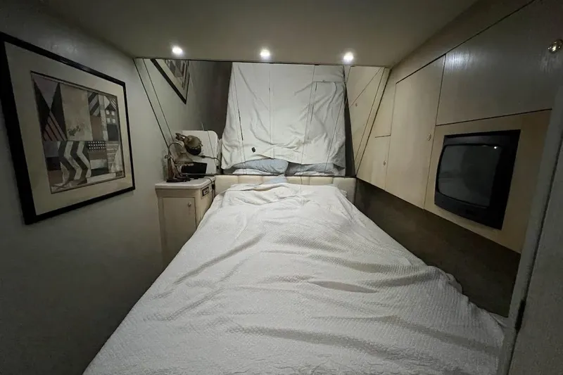 Our Trade II Yacht Photos Pics Cozy bedroom interior of 1996 Ocean Yachts 48 Super Sport with bed, artwork, and TV.