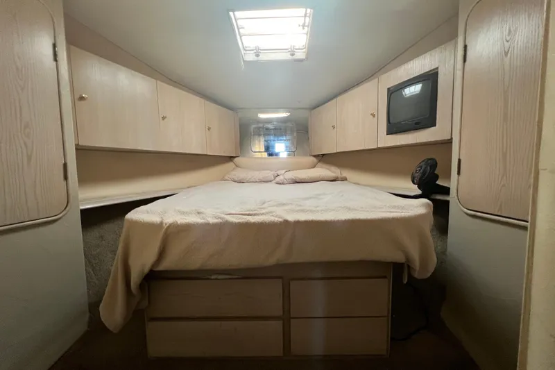 Our Trade II Yacht Photos Pics 1996 Ocean Yachts 48 Super Sport cabin interior with bed, storage, and TV.
