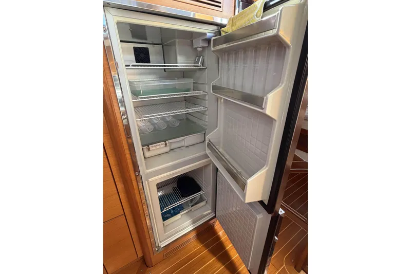 Heartbreaker Yacht Photos Pics Open refrigerator inside 2011 X-Yachts X-55, showcasing spacious interior and wooden flooring.