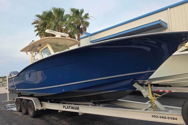  Yacht Photos Pics 2017 Scout 350 LXF boat on trailer, blue hull, parked near palm trees.