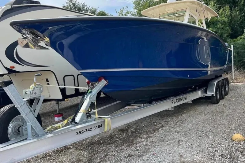  Yacht Photos Pics 2017 Scout 350 LXF boat on trailer, blue hull, parked outdoors.