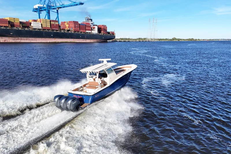  Yacht Photos Pics 2017 Scout 350 LXF boat cruising near a large cargo ship on a sunny day.