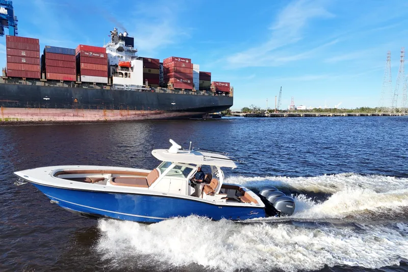  Yacht Photos Pics 2017 Scout 350 LXF boat cruising near a large cargo ship on a sunny day.
