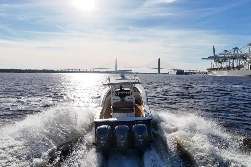  Yacht Photos Pics 2017 Scout 350 LXF boat cruising near a bridge and port under a sunny sky.