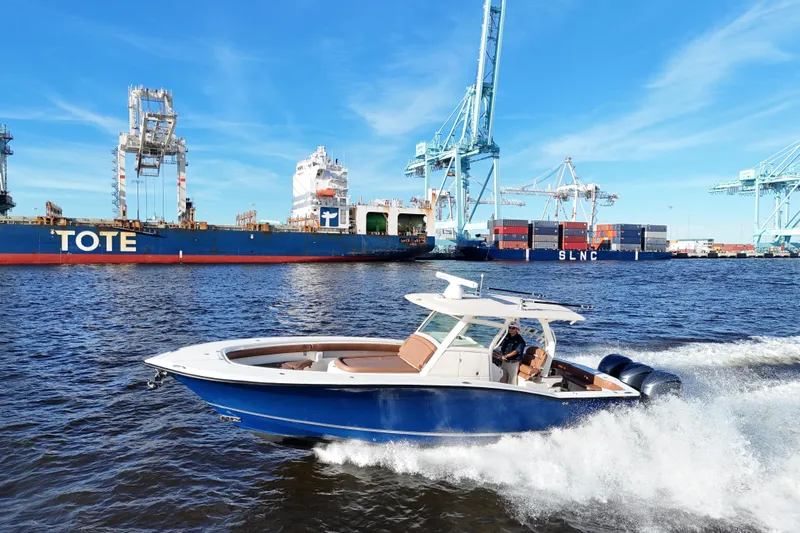  Yacht Photos Pics 2017 Scout 350 LXF boat cruising near cargo ships and cranes in a busy port.