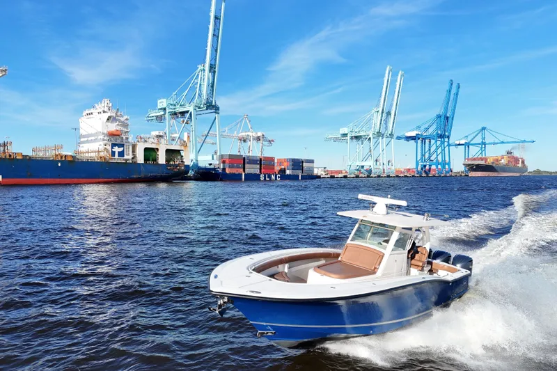  Yacht Photos Pics 2017 Scout 350 LXF boat cruising near a busy shipping port with cranes.