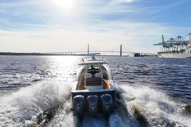  Yacht Photos Pics 2017 Scout 350 LXF boat cruising near a bridge and port under a sunny sky.