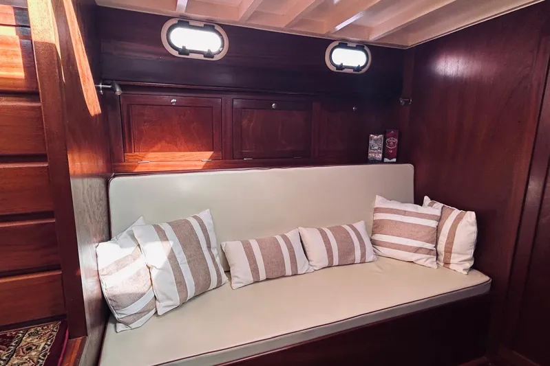 Aria Di Mare Yacht Photos Pics Cozy interior of 2013 Custom Classic Yawl with striped cushions and wooden paneling.