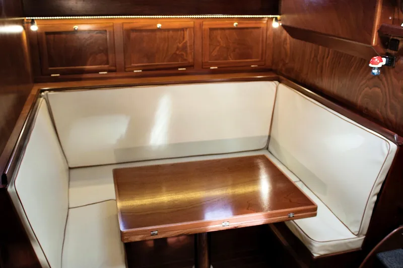 Aria Di Mare Yacht Photos Pics Elegant interior of 2013 Custom Classic Yawl with wooden table and cushioned seating.