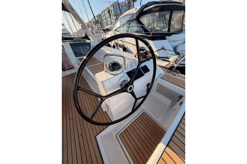 Bella Yacht Photos Pics Steering wheel of 2017 Beneteau Oceanis 45 sailboat with teak deck in marina.