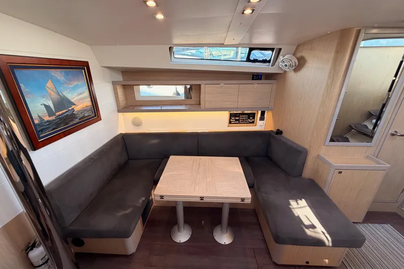 Bella Yacht Photos Pics 2017 Beneteau Oceanis 45 interior with cozy seating, wooden table, and nautical artwork.