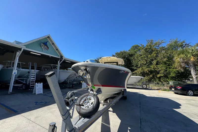  Yacht Photos Pics 2019 Chris-Craft Catalina 30 boat on trailer, parked outside dealership under clear blue sky.