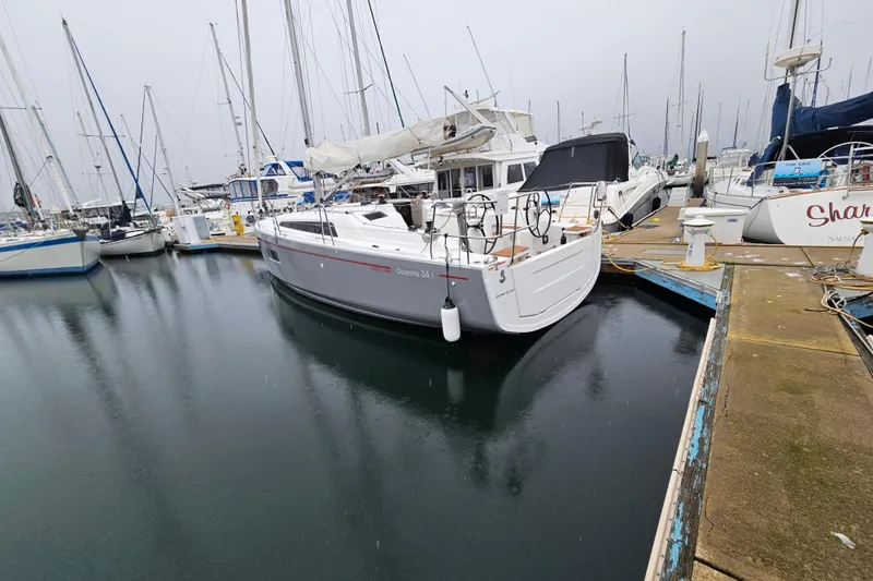 Cutting Edge Yacht Photos Pics 2023 Beneteau Oceanis 34.1 sailboat docked in a marina, surrounded by other boats.