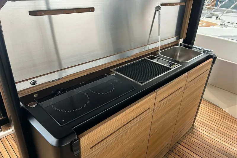  Yacht Photos Pics 2024 Cranchi A46 Luxury Tender kitchen with stove, sink, and wooden cabinetry.