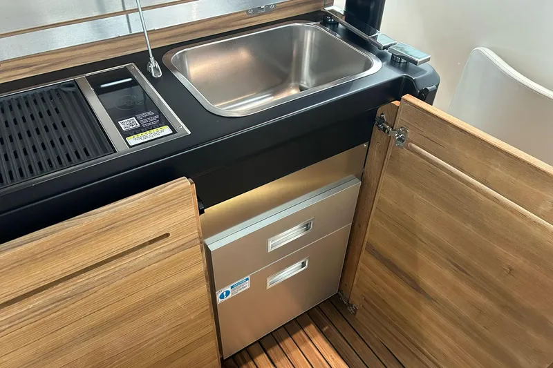 Yacht Photos Pics 2024 Cranchi A46 Luxury Tender kitchen area with sink, grill, and wooden cabinetry.