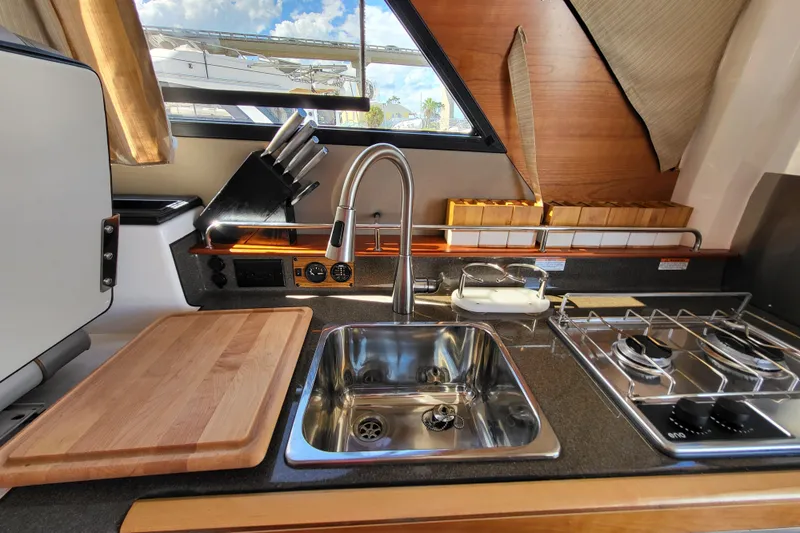 Tranquila Yacht Photos Pics 2023 Cutwater C-288 Coupe kitchen with sink, stove, and cutting board, featuring modern design.