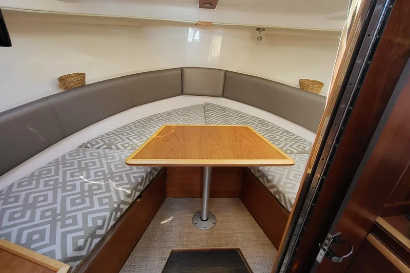 Tranquila Yacht Photos Pics 2023 Cutwater C-288 Coupe interior with cushioned seating and wooden table.